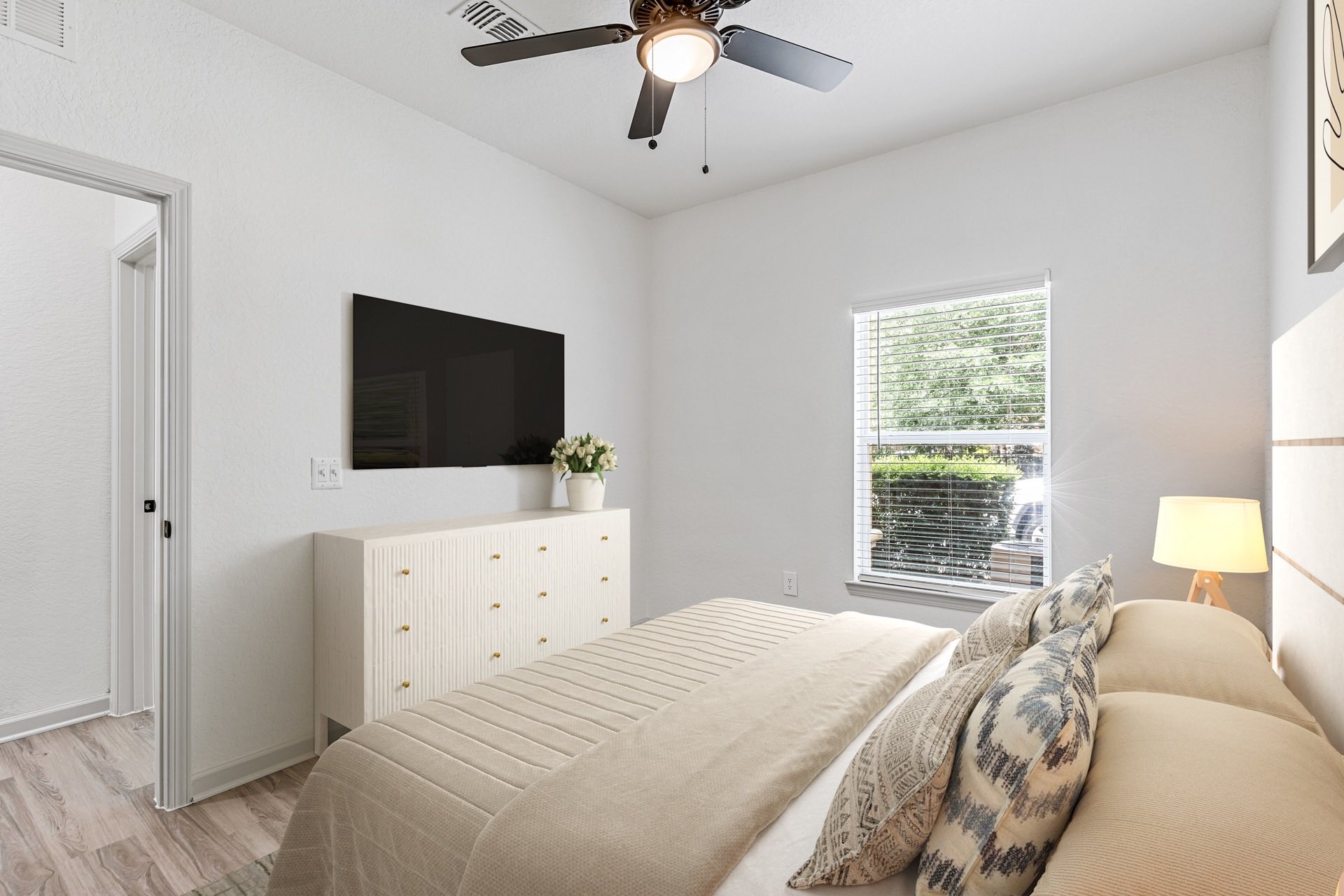 bedroom with medium sized window, wood style flooring, and mounted flat screen TV.